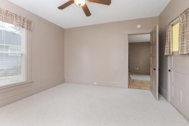 an empty room with chandelier fan and windows