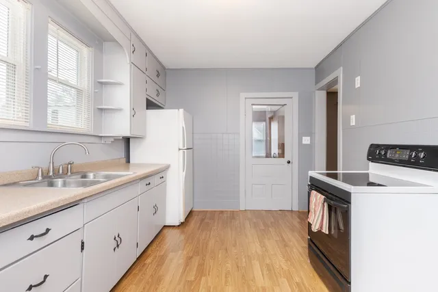 a kitchen with a sink a stove cabinets and wooden floor