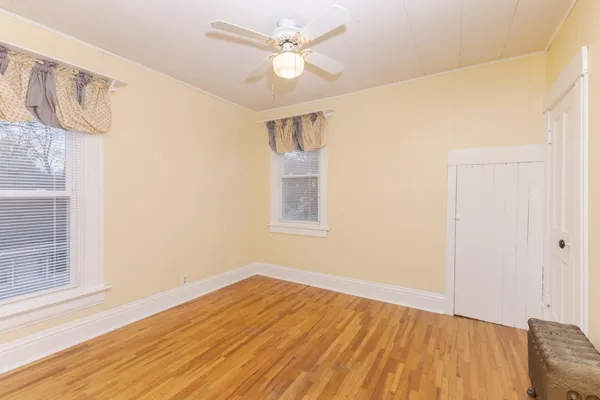 a view of empty room with wooden floor and fan
