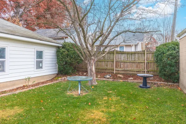 a view of a chair and table in backyard of the house