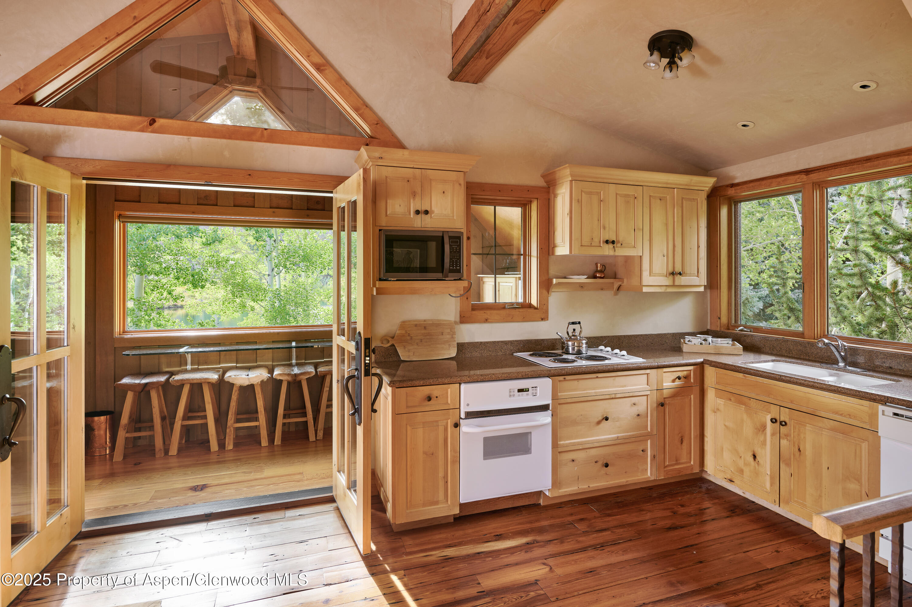 1900-1902 Snowmass Creek Road Snowmass, CO 81654 - Photo 42 of 74 a kitchen with stainless steel appliances granite countertop a stove a sink and a refrigerator with wooden floor