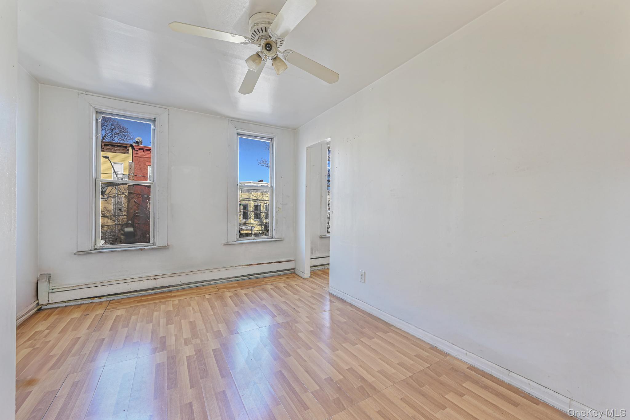 12-16 30th Drive Queens, NY 11102 - Photo 7 of 34 a view of empty room with wooden floor and fan