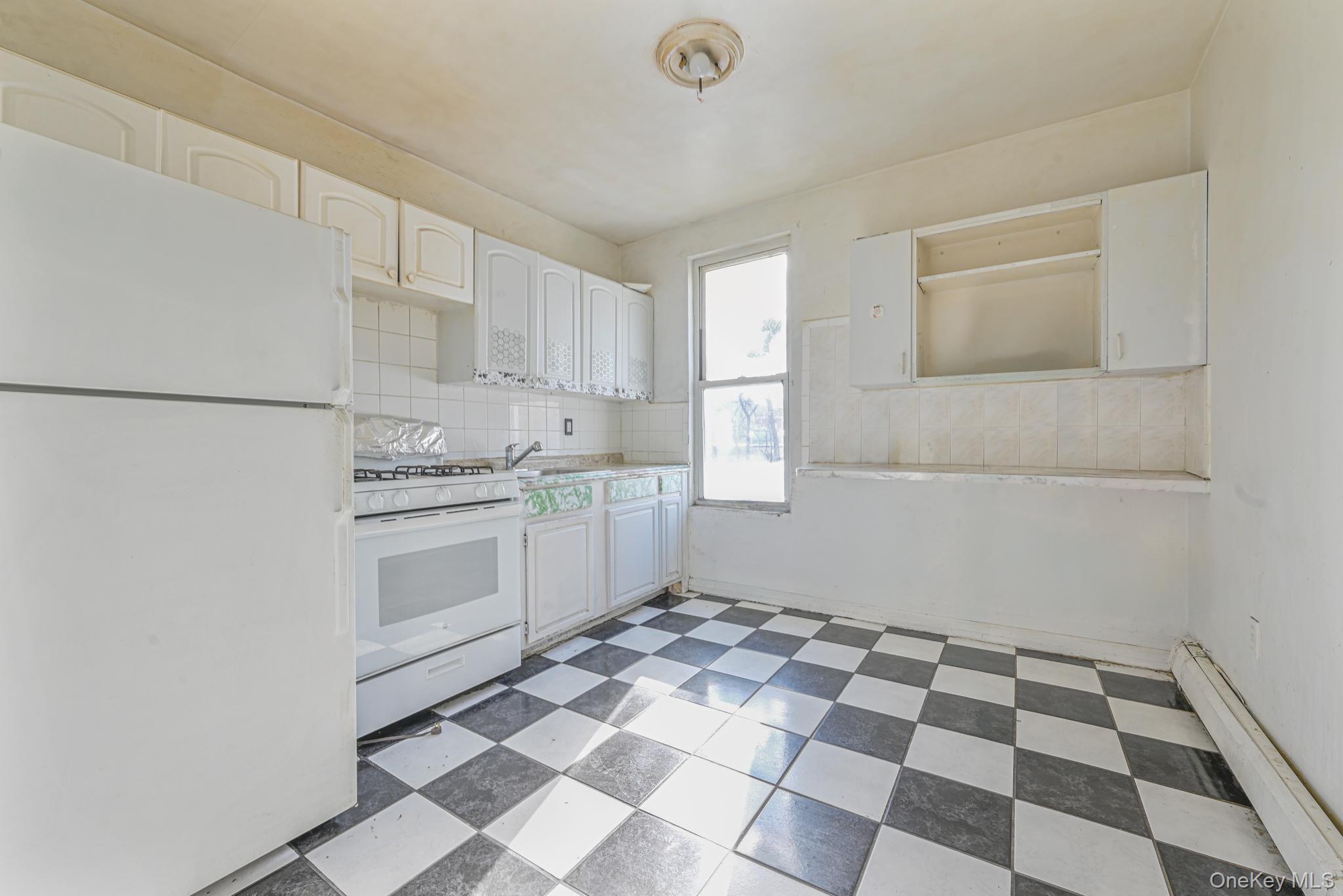 12-16 30th Drive Queens, NY 11102 - Photo 9 of 34 a kitchen with a checkered floor and white cabinets