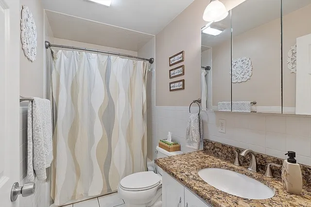 a bathroom with a granite countertop sink vanity mirror and toilet