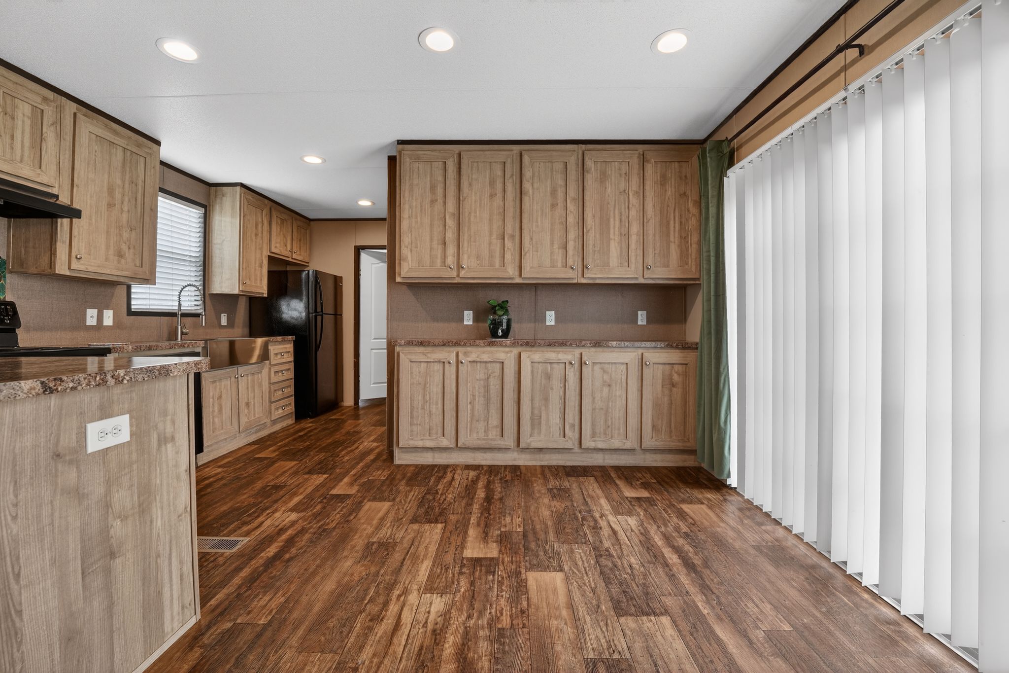 16 4th Street Maxwell, TX 78656 - Photo 22 of 35 a kitchen with stainless steel appliances granite countertop a refrigerator a sink dishwasher and wooden cabinets with wooden floor
