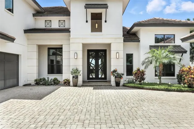 a large white kitchen with lots of counter space a sink and living room view