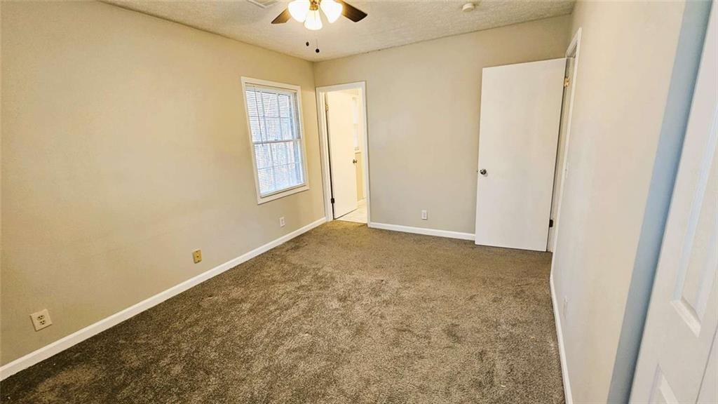 2172 Nancy Way Loganville, GA 30052 - Photo 17 of 21 an empty room with a chandelier fan and windows