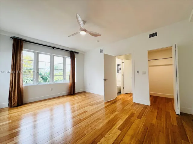 a view of empty room with wooden floor and fan