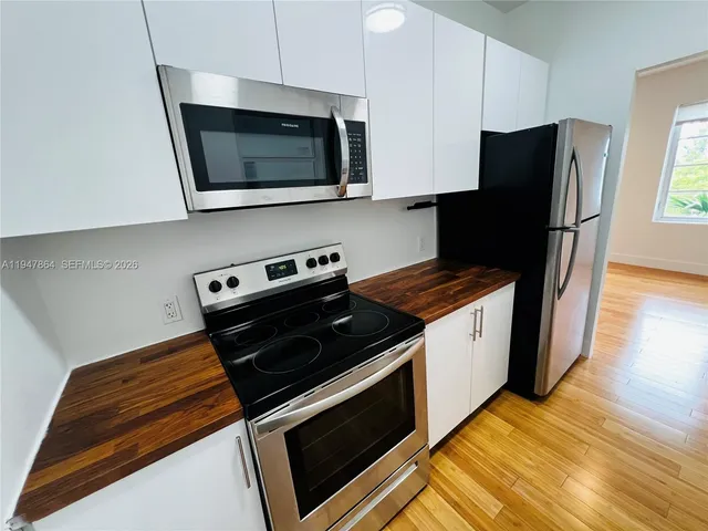 a view of a refrigerator in kitchen and an empty room
