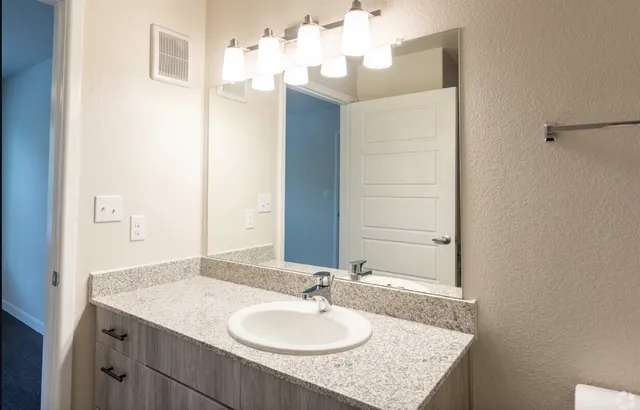 a bathroom with a granite countertop sink and a mirror
