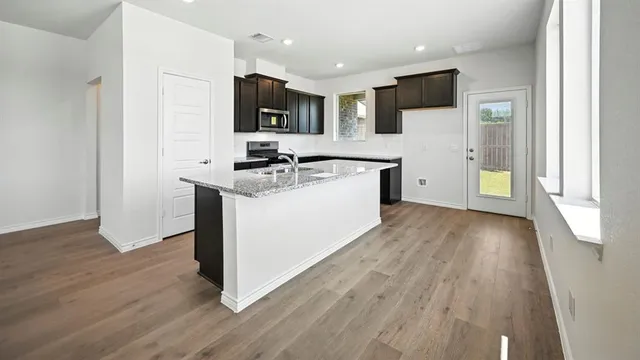 a large kitchen with granite countertop a sink and a stove top oven