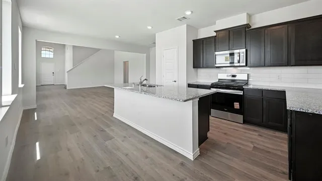 a kitchen with granite countertop cabinets stove top oven and microwave