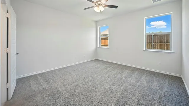 an empty room with windows and fan