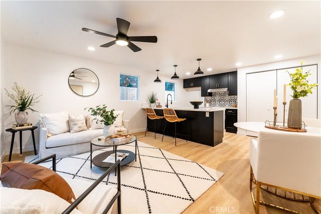 a living room with furniture kitchen view and a large window