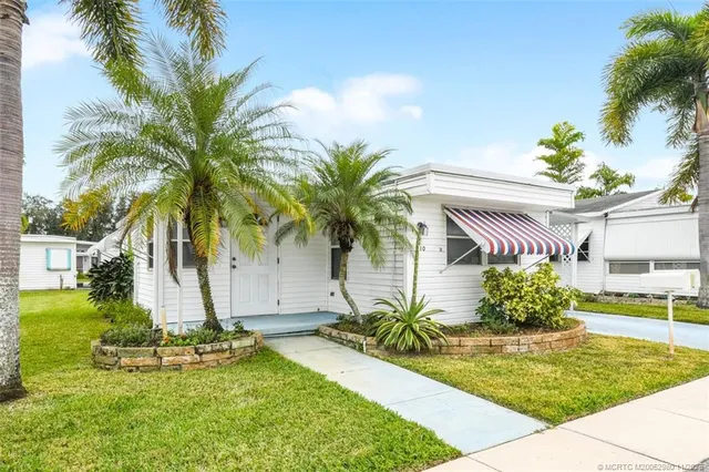 a view of a house with a yard and palm trees