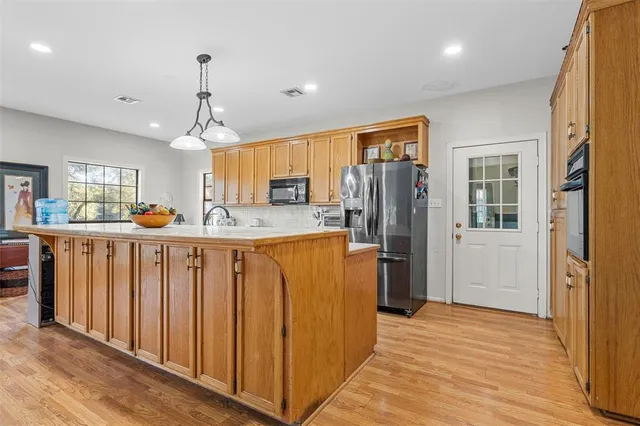 a kitchen with stainless steel appliances granite countertop a refrigerator a sink dishwasher and wooden cabinets with wooden floor
