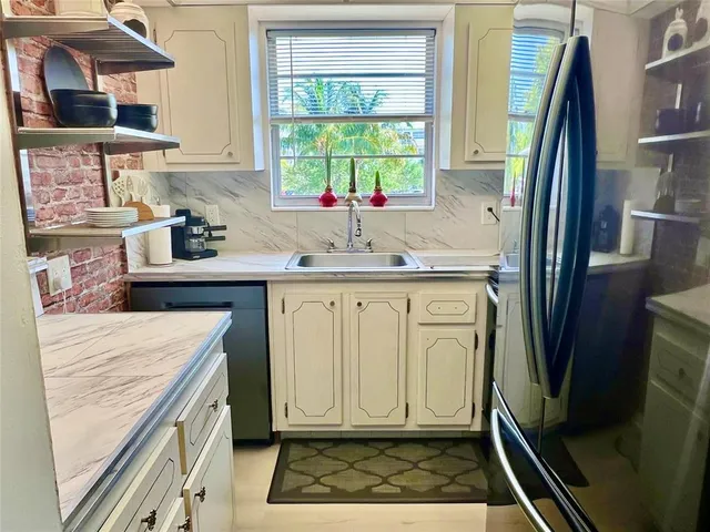 a kitchen with white cabinets and sink