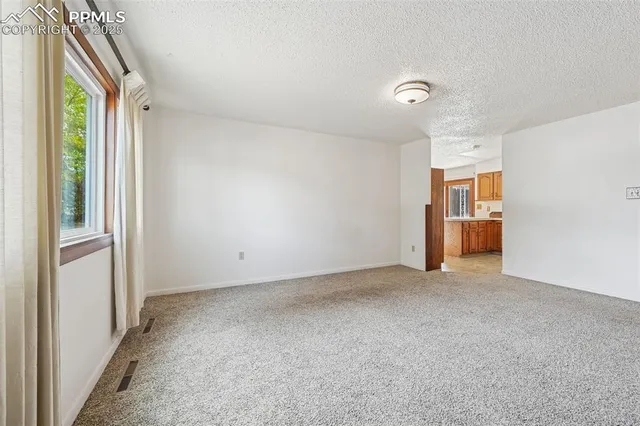a view of empty room with window and refrigerator