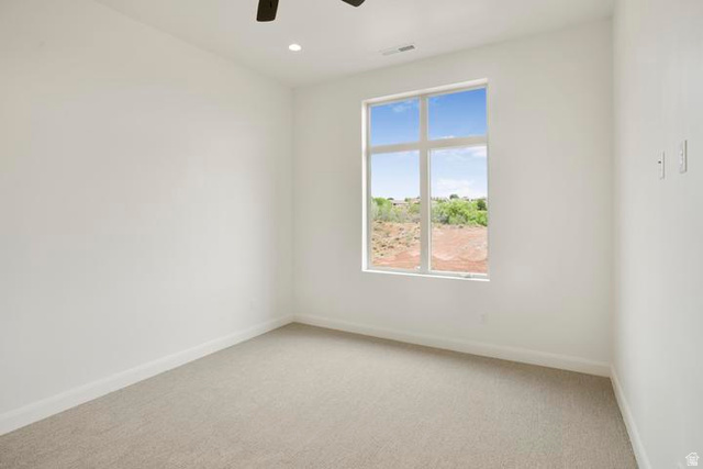 990 Manen Street Washington, UT 84780 - Photo 16 of 43 Light-filled room featuring a large window, neutral carpeting, white baseboards, and a ceiling fan with integrated lighting