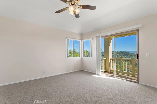 a view of a room with a ceiling fan and carpet