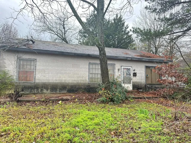 a backyard of a house with large trees and brick wall
