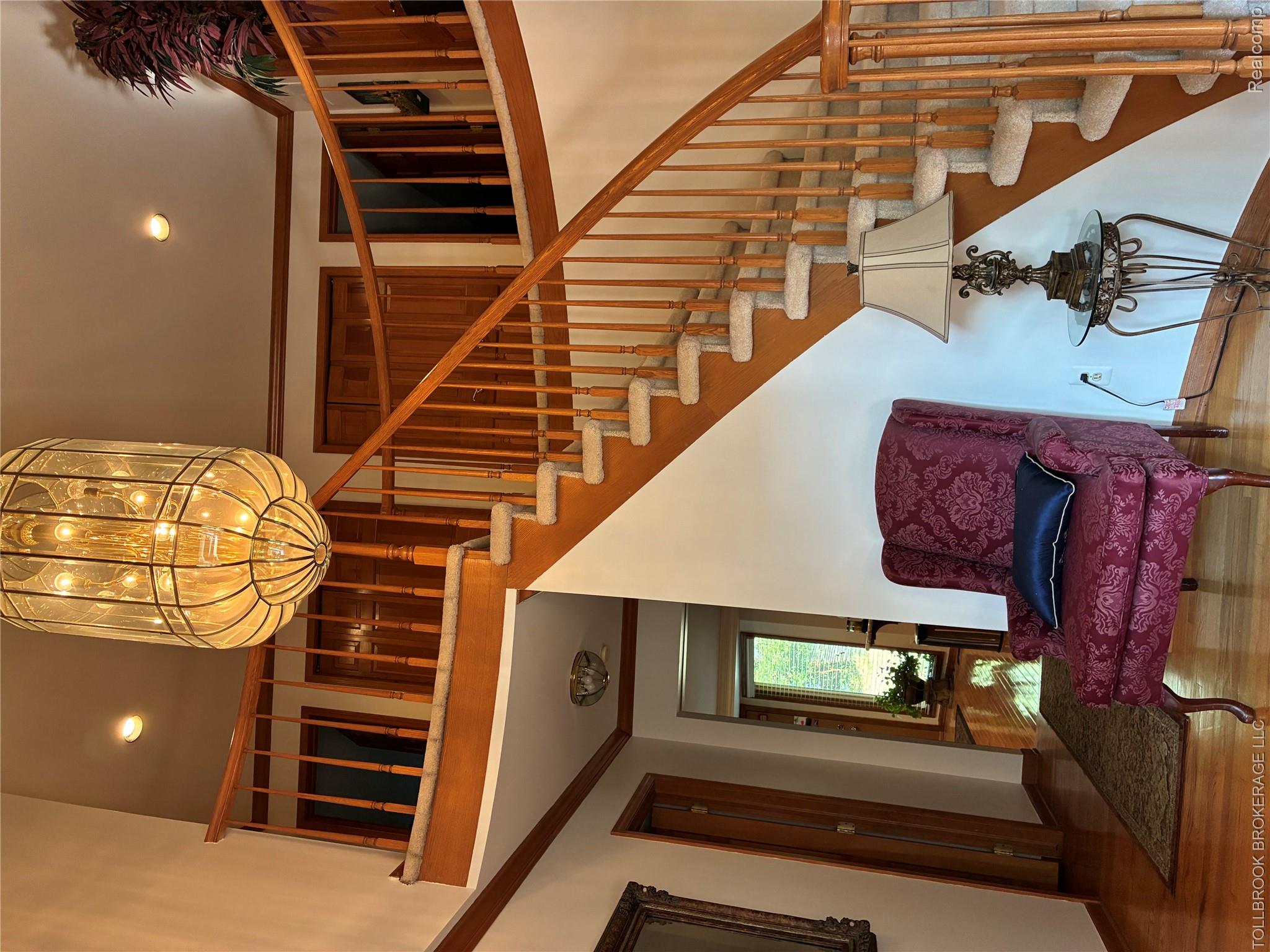 Grand entryway featuring a large suspended chandelier, a curved staircase with wood railings, and polished wood-finish flooring