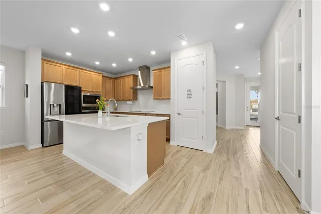 a large kitchen with stainless steel appliances kitchen island a large counter top and a refrigerator