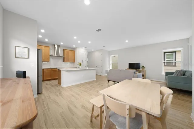 a large white kitchen with stainless steel appliances kitchen island a stove a sink a refrigerator and chairs