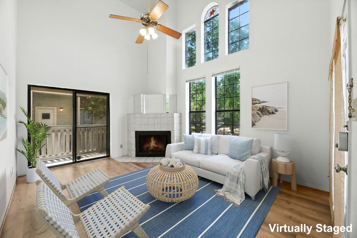 4409 Speedway, Unit 201 Austin, TX 78751 - Photo 2 of 16 Living area featuring wood finished floors, a fireplace, a towering ceiling, and a ceiling fan