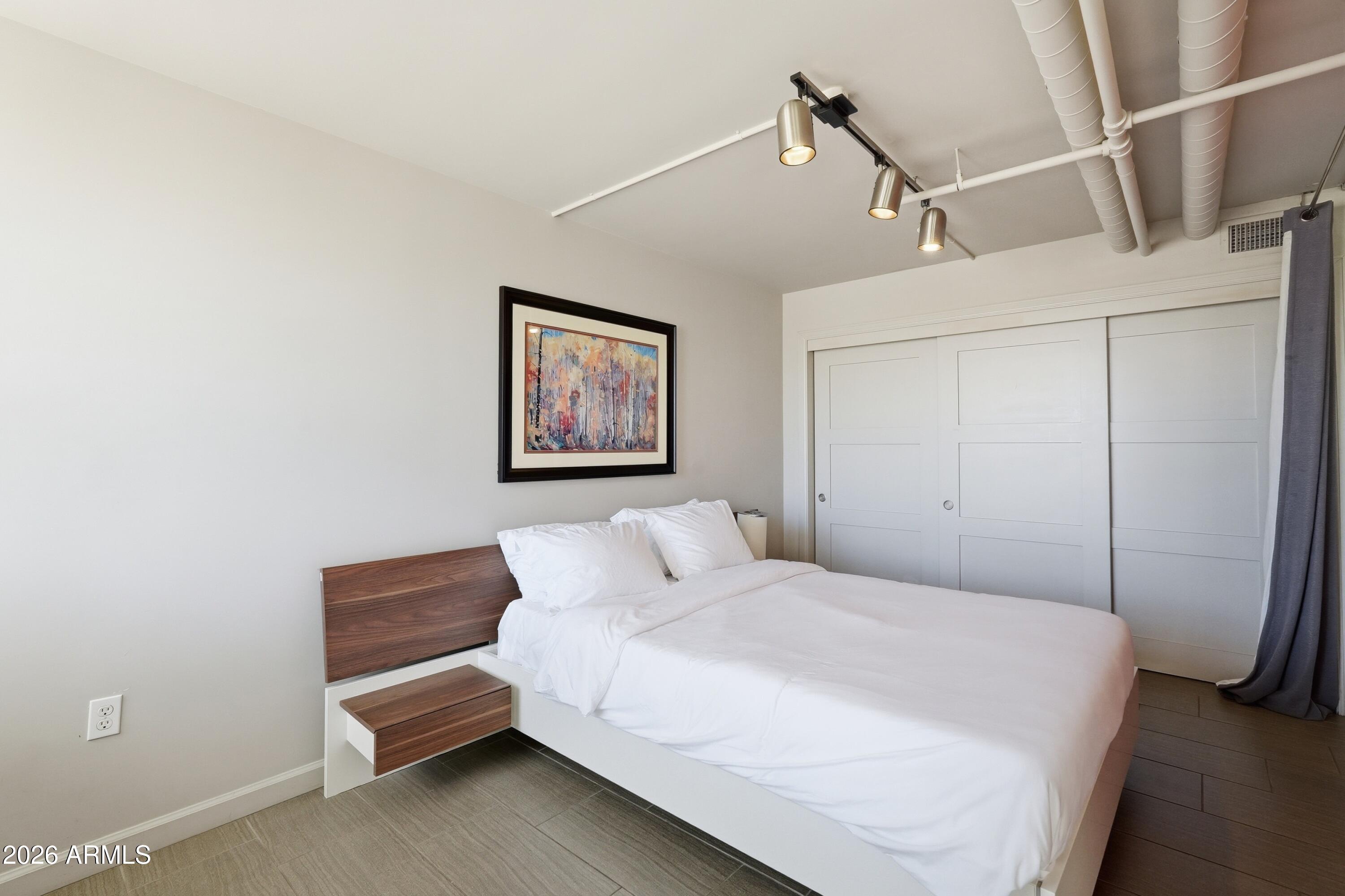535 West Thomas Road, Unit 210 Phoenix, AZ 85013 - Photo 19 of 40 a bedroom with a bed and a chandelier