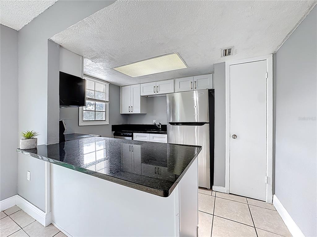 2753 L B McLeod Road, Unit D Orlando, FL 32805 - Photo 14 of 48 a kitchen with stainless steel appliances granite countertop a refrigerator a sink a stove and a refrigerator with wooden floor