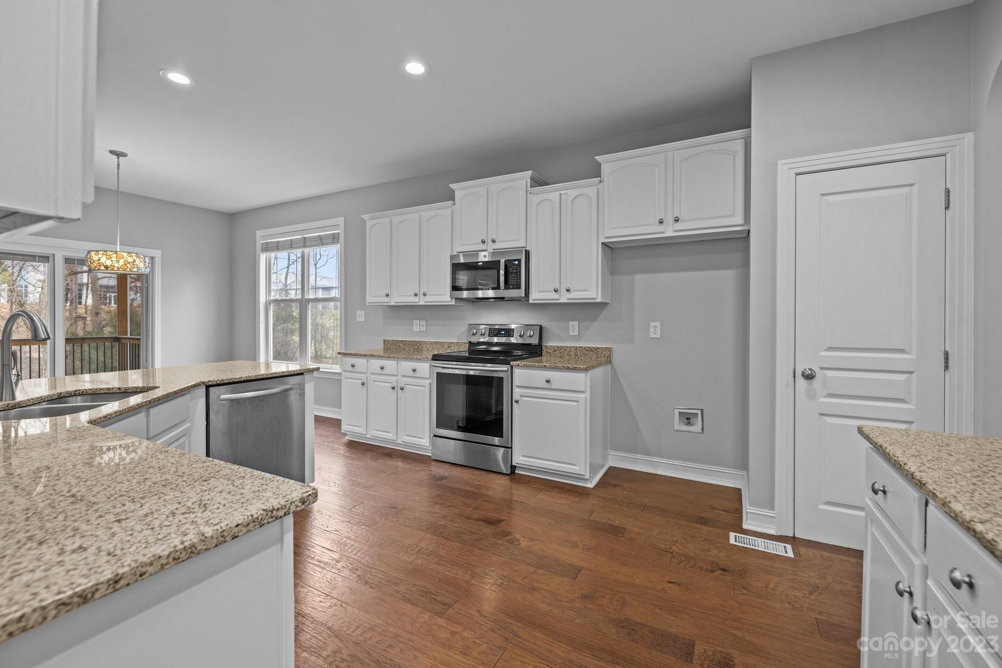 10304 Glenmeade Road Cornelius, NC 28031 - Photo 24 of 47 a kitchen with granite countertop white cabinets and stainless steel appliances