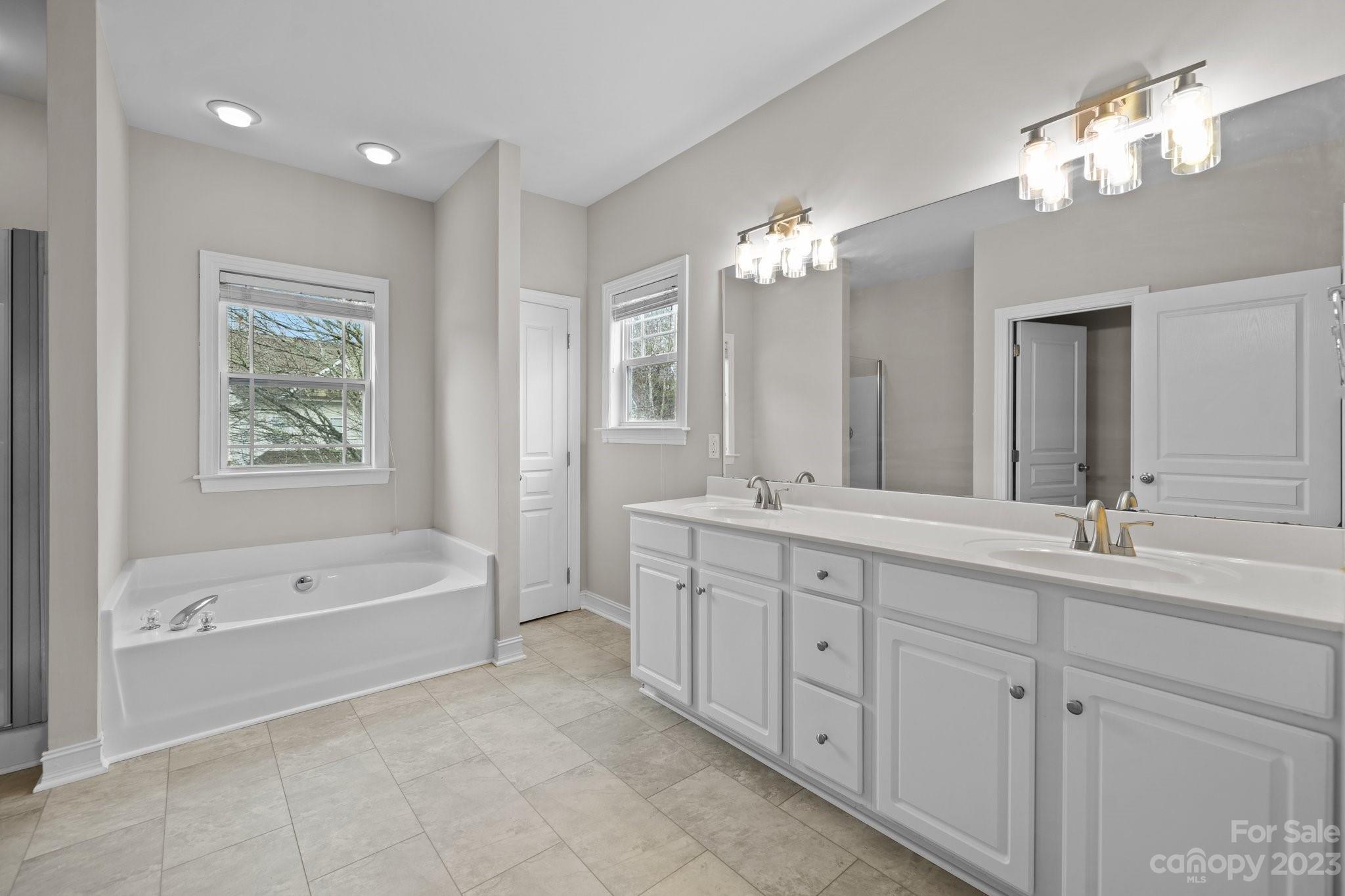 10304 Glenmeade Road Cornelius, NC 28031 - Photo 38 of 47 a spacious en suite bathroom with a tub double sink and mirror
