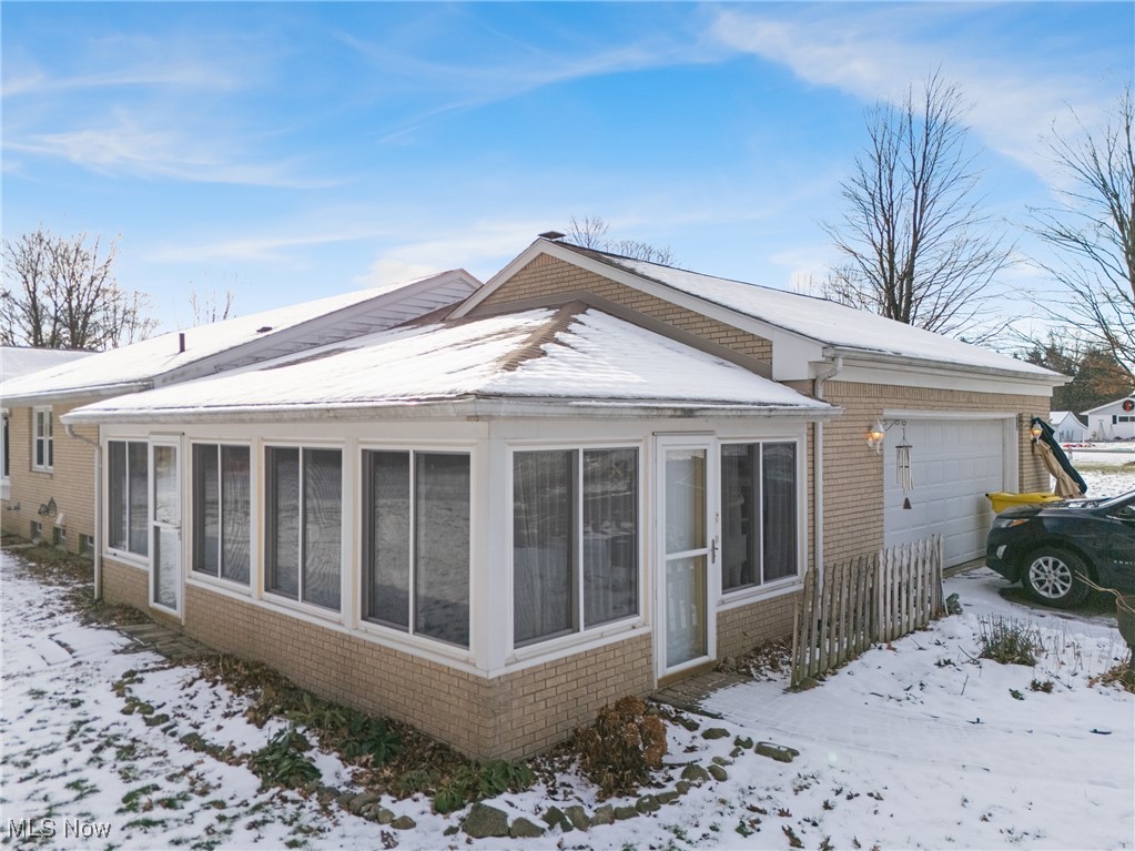 14965 Seacrist Road Salem, OH 44460 - Photo 33 of 43 View of snowy exterior featuring brick siding, a garage, and a sunroom