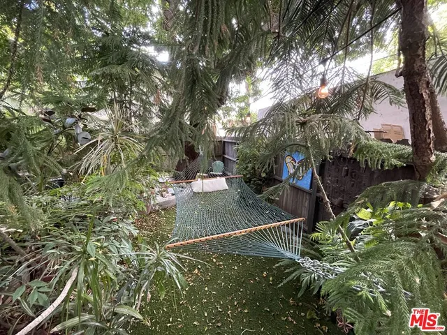 a view of a backyard with table and chairs potted plants and large tree