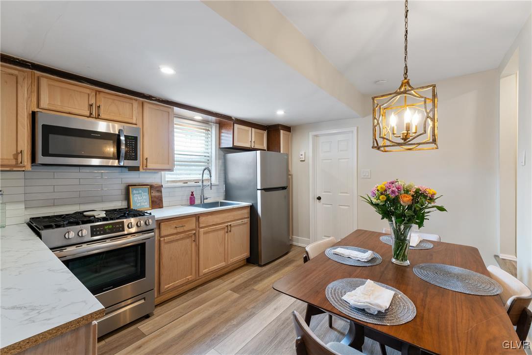 1226 Railroad Street Bethlehem, PA 18015 - Photo 5 of 20 a kitchen with stainless steel appliances a kitchen island hardwood floor sink stove dining table and chairs