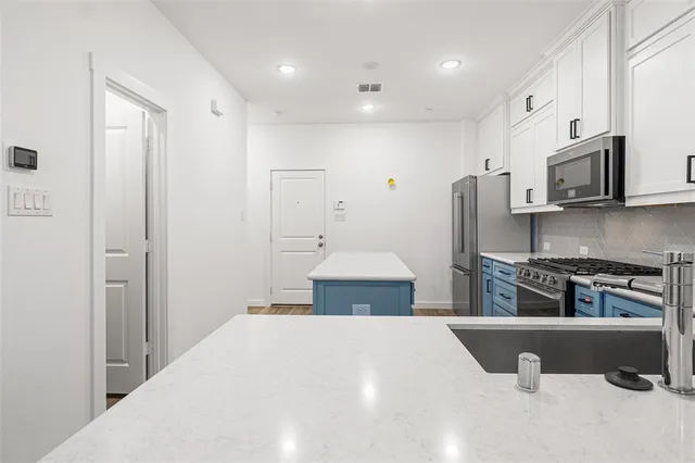 a kitchen with stainless steel appliances a refrigerator and a stove top oven