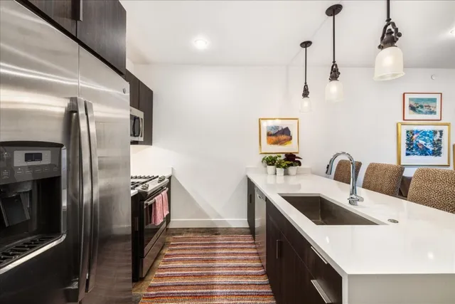 a kitchen with stainless steel appliances granite countertop a sink and a refrigerator