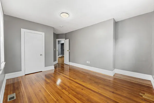a view of a bedroom with wooden floor and window