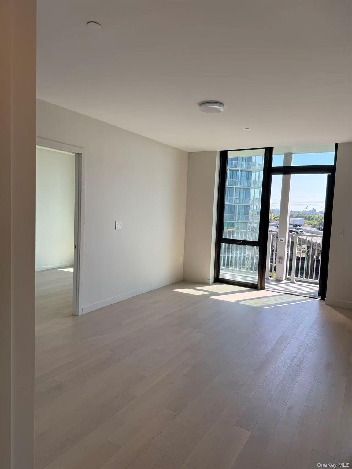 131-02 40th Road, Unit 6G Queens, NY 11354 - Photo 9 of 11 an empty room with large windows and wooden floor