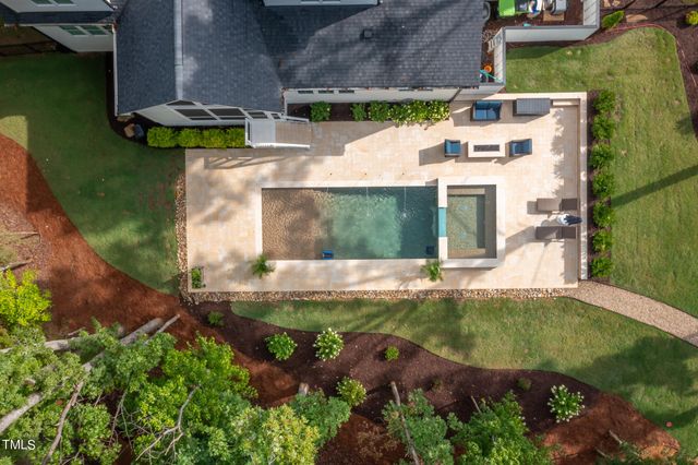 an aerial view of a house with swimming pool and large trees