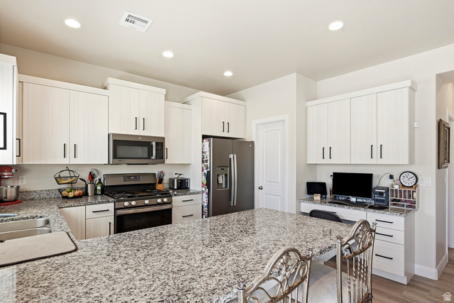 668 East Fiddlers Canyon Road, Unit 6 Cedar City, UT 84721 - Photo 10 of 36 Kitchen featuring a large island with a stone countertop, white cabinetry with black hardware, stainless steel appliances, and recessed lighting