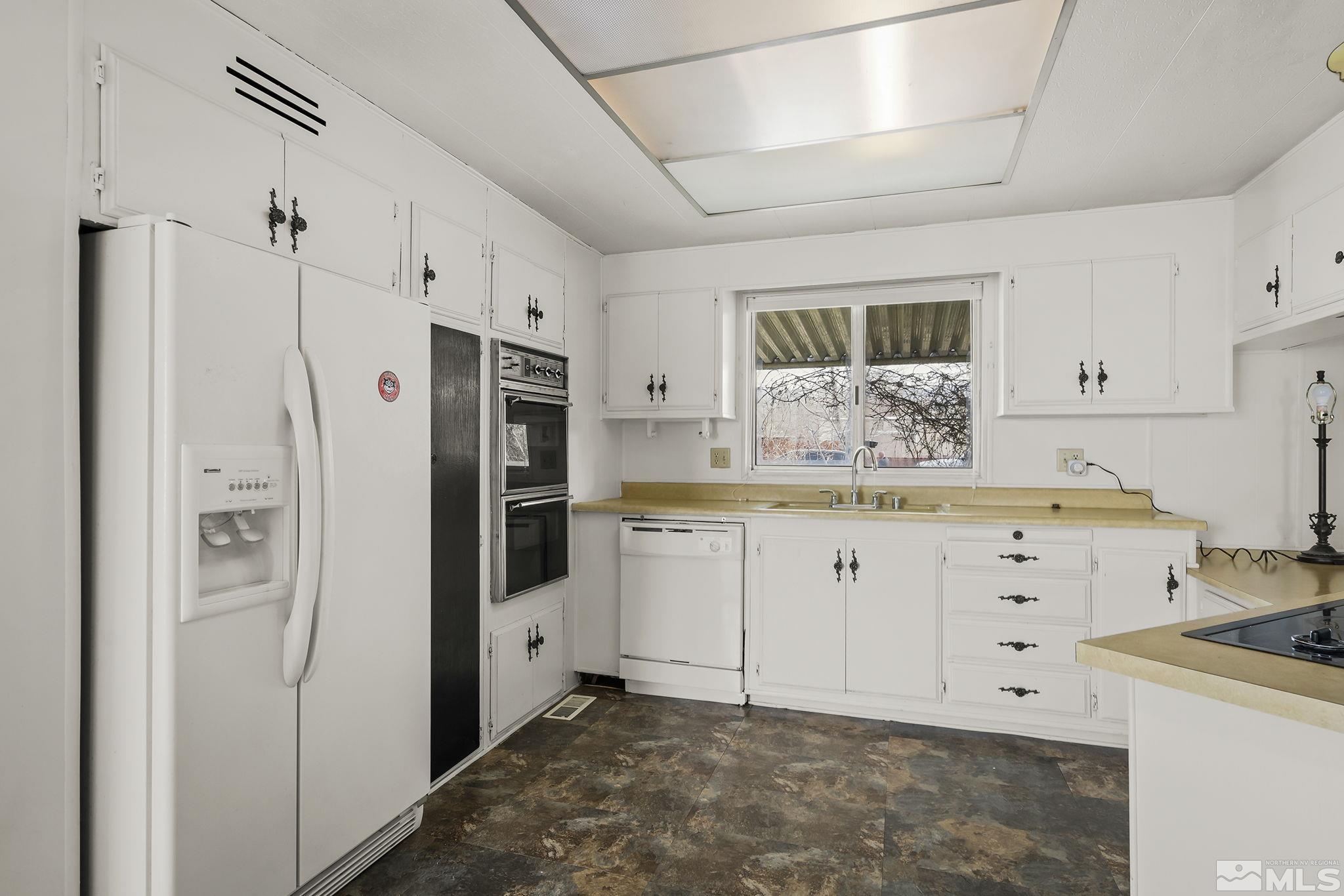16305 Rhyolite Circle Reno, NV 89521 - Photo 8 of 16 a kitchen with white cabinets and refrigerator