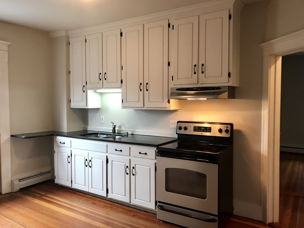 27-29 Topsfield Road, Unit 4 Ipswich, MA 01938 - Photo 6 of 22 a kitchen with granite countertop white cabinets and stainless steel appliances