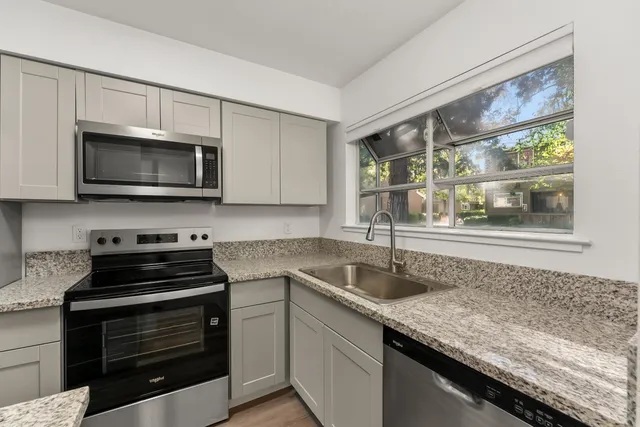 a kitchen with granite countertop a stove sink and microwave