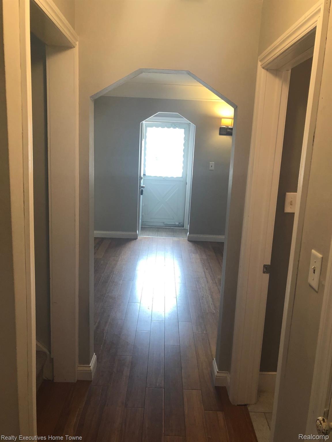 2427 Cambridge Road Berkley, MI 48072 - Photo 11 of 17 Hallway featuring wood-finish flooring, a white arched doorway, and light gray wall paint
