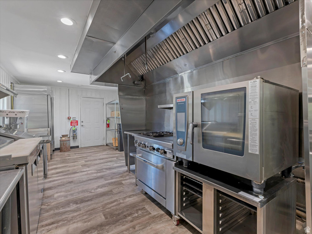 12825 South Fort Street Draper, UT 84020 - Photo 44 of 52 Commercial-grade kitchen featuring stainless steel appliances, extensive stainless steel counters, a large professional range with a powerful ventilation hood, and recessed lighting