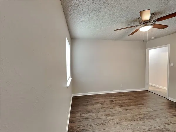 an empty room with wooden floor fan and windows