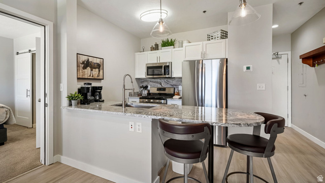1364 Still Water Drive, Unit R2012 Heber City, UT 84032 - Photo 7 of 30 Modern kitchen featuring white cabinetry, stainless steel appliances, a stone countertop with an integrated sink, and pendant lighting