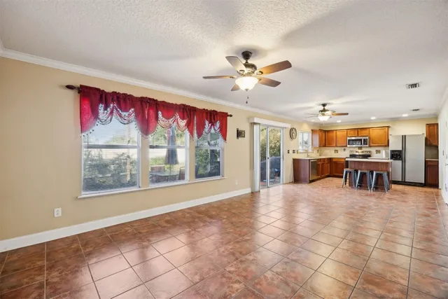 en empty room with windows and chandelier fan